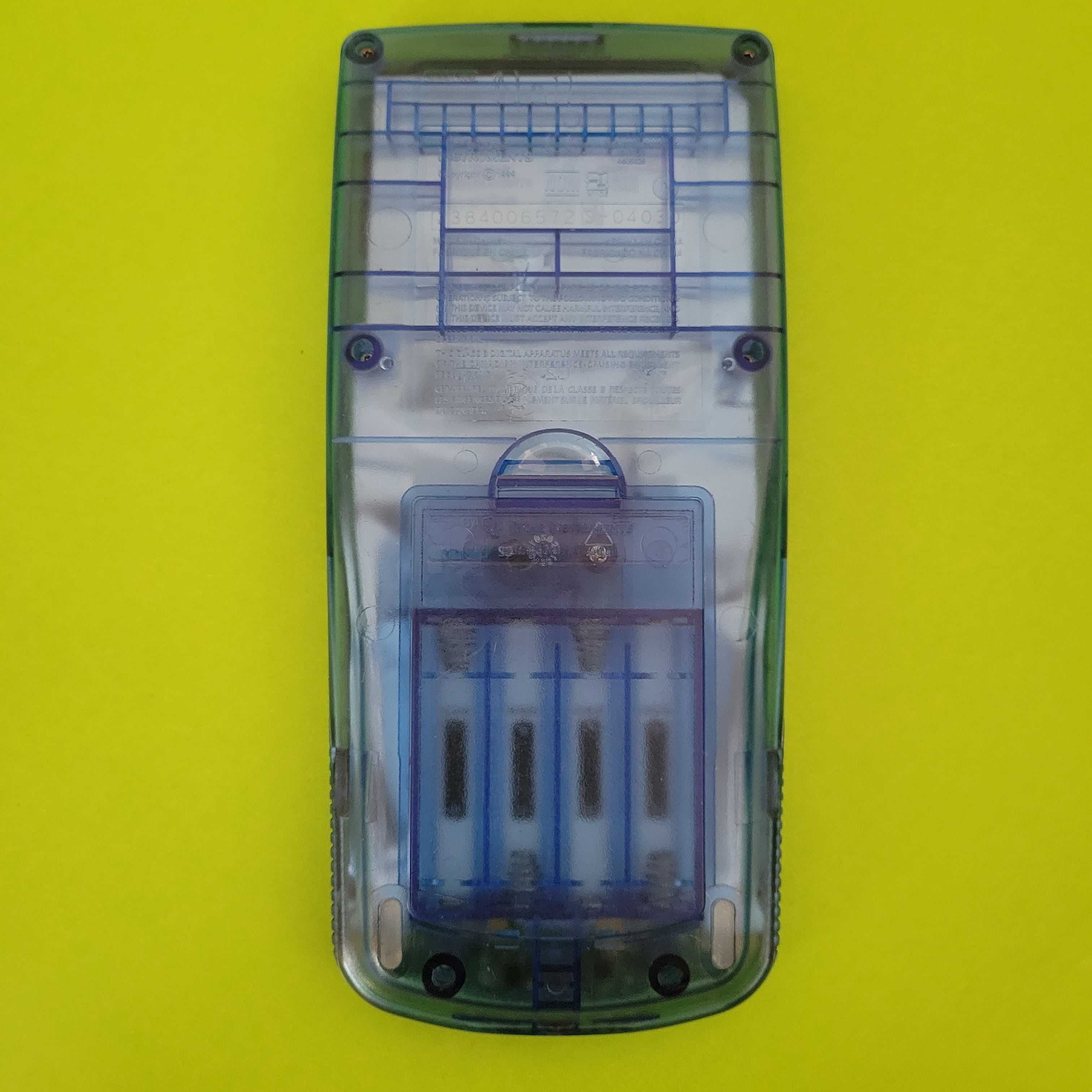 An image of the back of a texas instruments ti83 plus blue graphing calculator